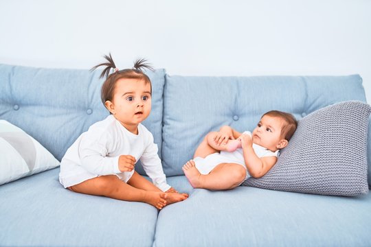 Beautiful infant happy girls playing together at home kindergarten sitting on the sofa