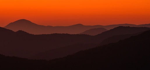 Fototapeta na wymiar Haze Separates Layers of Orange Mountains