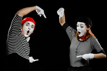 Mimes points at something invisible. Their faces express shock and amazement
