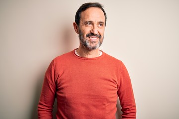 Obraz premium Middle age hoary man wearing casual orange sweater standing over isolated white background smiling looking to the side and staring away thinking.