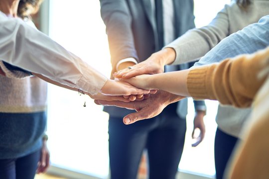 Group of business workers standing with hands together at the office