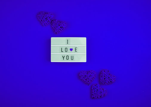 Words i love you on the light box on a blue background with hearts. Place for text, abstract content. - Powered by Adobe