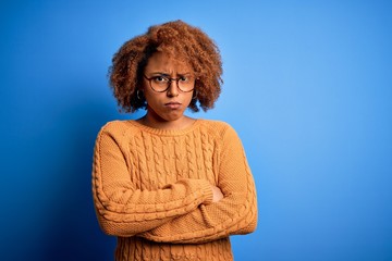 Young beautiful African American afro woman with curly hair wearing casual sweater skeptic and...
