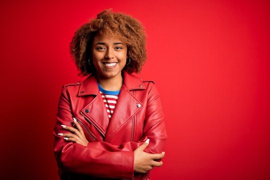 Young beautiful African American afro woman with curly hair wearing casual red jacket happy face smiling with crossed arms looking at the camera. Positive person. - Powered by Adobe