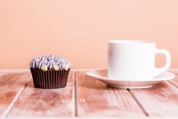 Chocolate delicious cupcake with cream and fragrant coffee with milk on a white wooden table.