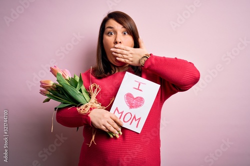Beautiful plus size woman celebrating mothers day holding message and bouquet of tulips cover mouth with hand shocked with shame for mistake, expression of fear, scared in silence, secret concept