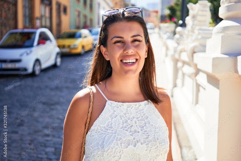 Wall mural Young beautiful woman smiling happy walking on city streets on a sunny day of summer