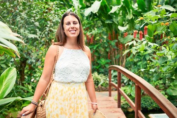 Young beatiful woman smiling happy and cheerful at butterfly garden on a sunny day of summer