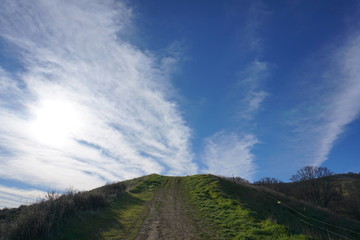 hiking trail green grass white clouds
