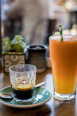 Glass of espresso with glass of juice with straw.