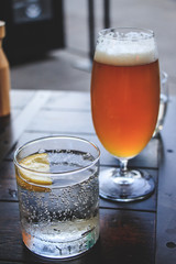 Glass of fizzy drink with lemon and glass of beer.