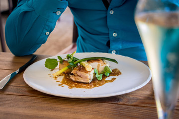 Dinner plate with chicken, vegetables en sauce and glass of champagne.