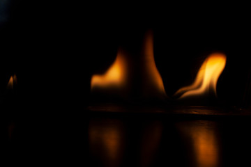 Fiery background. Flames of fire in the dark. Flame texture. Tongues of fire rise smoothly. A simple background of yellow shades. Burning gel for ignition. Ignition of vapors. Fire is danger.