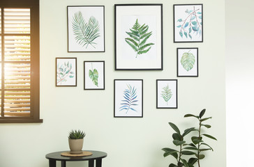 Living room interior with paintings of tropical leaves on white wall