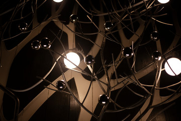 Beautiful lamps. Designer lights. Metal balls as an element of decor. Beautiful interior. Dark background with bright lamps on curved steel racks.