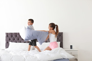 Fototapeta premium Happy children having pillow fight in bedroom