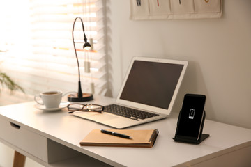 Stylish workplace with laptop, mobile phone and wireless charger