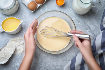 Woman preparing batter for thin pancakes at grey table, top view - obrazy, fototapety, plakaty