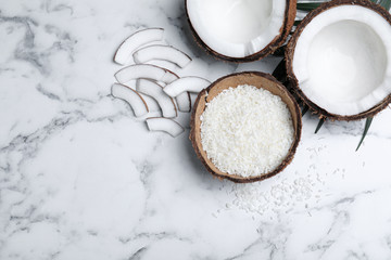 Flat lay composition with fresh coconut flakes on white marble table. Space for text