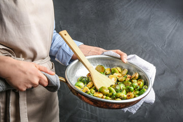 Woman holding pan with roasted Brussels sprouts, closeup