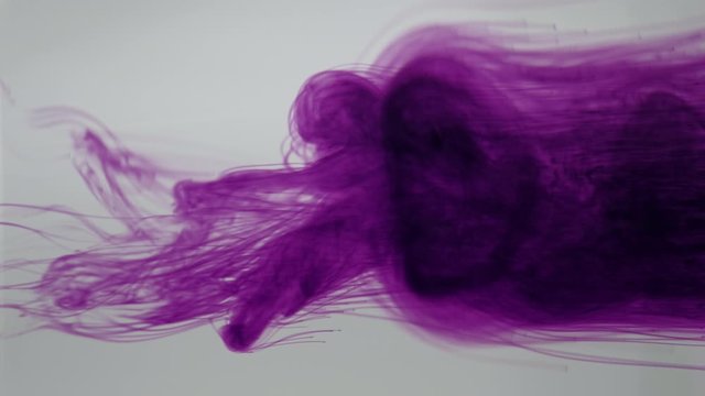 Colourful dynamic abstract background. Potassium permanganate crystals in the water. Close up. 4K resolution.