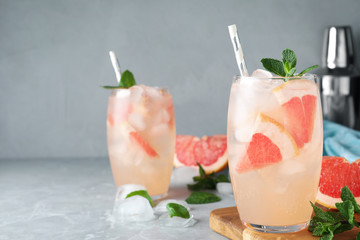 Glasses of fresh cocktail with grapefruit on grey marble table. Space for text