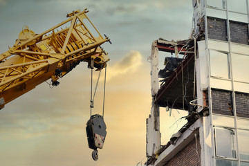 Crane lifting hook at construction site with derelict building for demolition