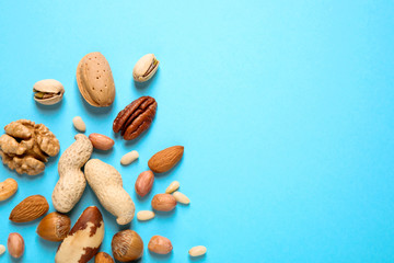 Different delicious nuts on light blue background, flat lay. Space for text