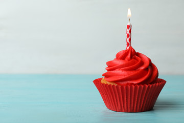 Delicious birthday cupcake with cream and burning candle on blue wooden table. Space for text - Powered by Adobe