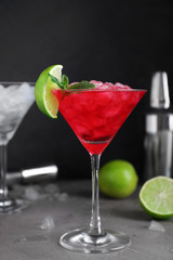 Tasty red alcoholic cocktail in martini glass on light grey table