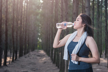 Beautiful young woman drinking water bottle after exercise fitness