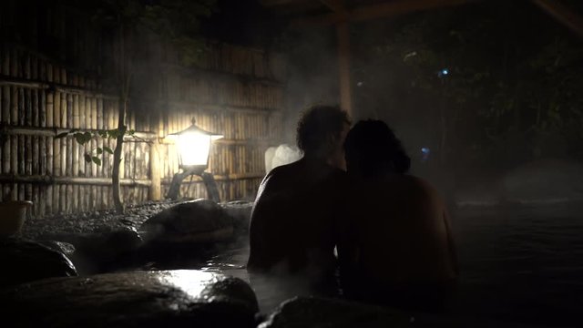 Silhouette of couple sitting inside outdoor Onsen,Japanese hot spring bath