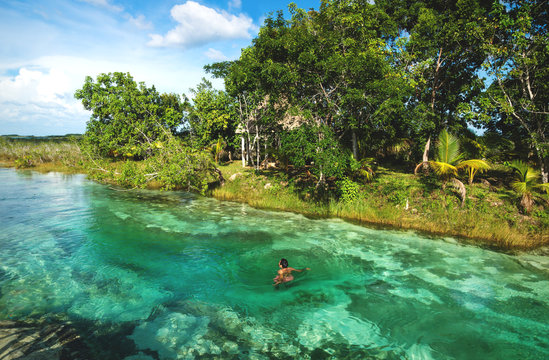 Man in rapids at seven colored lagoon surrounded by tropical plants in Bacalar, Quintana Roo, Mexico