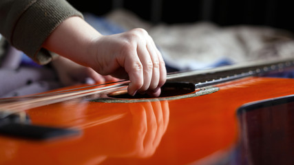 Obraz na płótnie Canvas little girl tries to tear the strings on the guitar