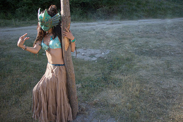 Beautiful tanned girl in the mask of an ancient goddess. The dancer shows movement. Mysterious girl beckons guys. A stranger is looking for a man. Beautiful body of a woman. Unusual high quality mask.
