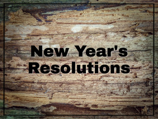 inspirational text of new year's resolutions on wood surface with vintage background