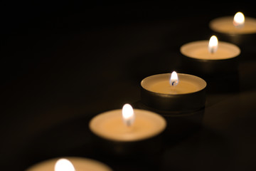 Fototapeta na wymiar Small romantic candles against a dark background