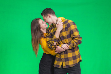 A couple in love happy together on green background, hugging and kissing.