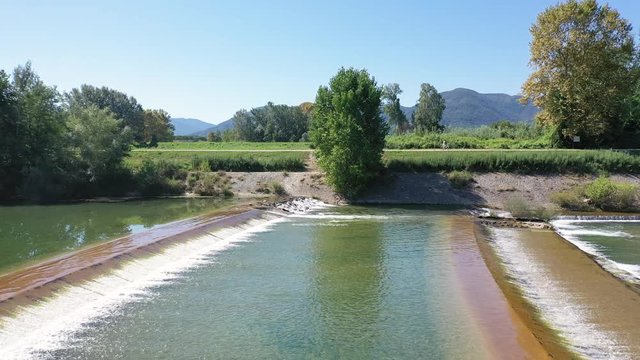 a person pushing his bike along the Serchio river next to Lucca city, Tuscany, Italy