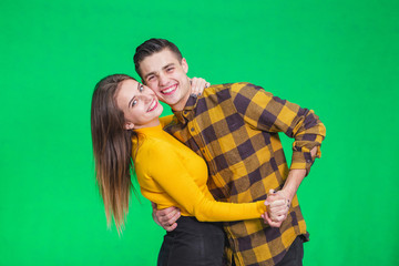 Young beautiful couple in love, dancing on green background, celebrating some special occasion.