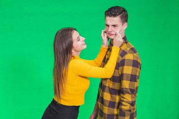 Girl pinching guy's cheeks, making fyn, he is scowling his face, looking completely annoyed.