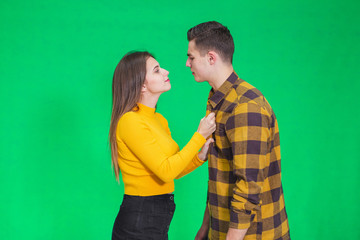 Naughty young lady is going to kiss her lover, pulling him close to her.