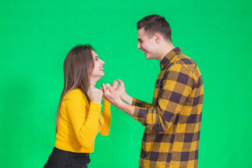 Cheerful young couple clenching their fists, saying yes, celebrating their success over green background.