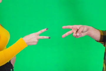 Cropped hands of people playing rock paper scissors isolated on green background.