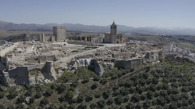 D-log aerial footage of Alcala de Real medieval fortified hilltop castle and church in Andalusia Spain
