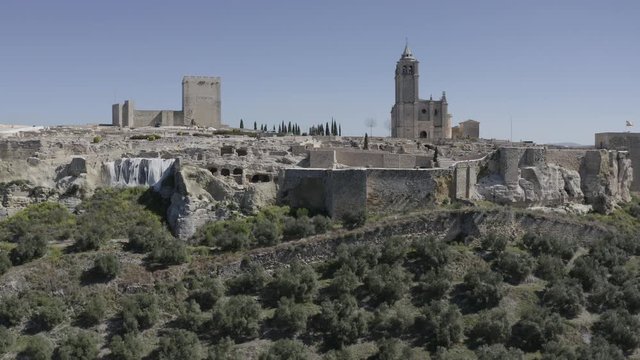 D-log aerial footage of Alcala de Real medieval fortified hilltop castle and church in Andalusia Spain