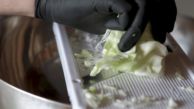 Cutting cabage using a mandoline preparing coleslaw salat for barbeque wearing a black rubber glove