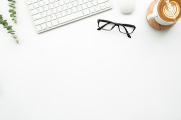 White minimal office desk table with computer tools, cup of latte coffee and supplies. Top view with copy space, flat lay.