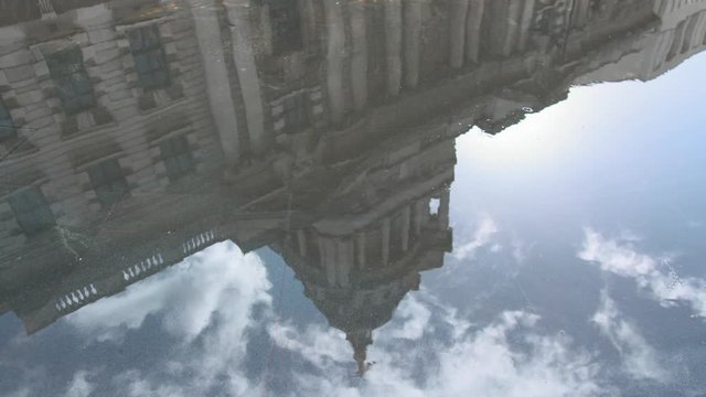 Looking down at a pool of water with the reflection of the Old Bailey in it