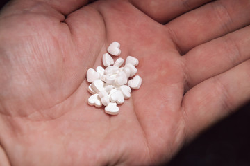 A lot of tiny white hearts on the palm. Heart-shaped pills.